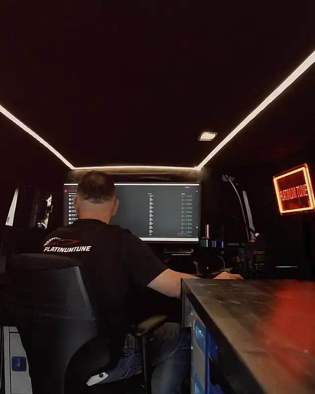 Mobile remapping: a tuner at the monitor under the LED ceiling, the red Platinum Tune neon sign over the workbench
